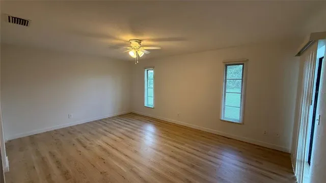 a view of empty room with wooden floor and fan