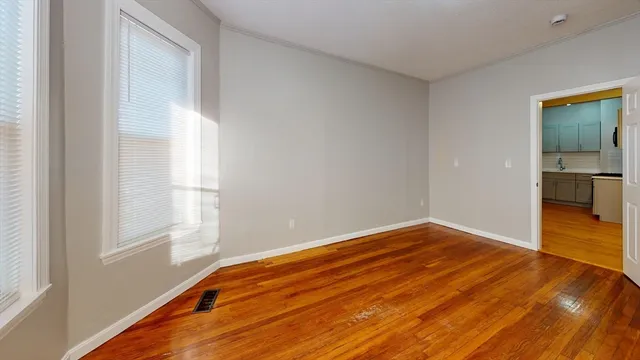 a view of empty room with wooden floor and fan