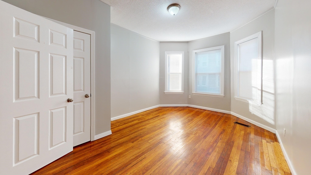 8 Wardman Road, Unit 1 Boston, MA 02119 - Photo 5 of 14 wooden floor in an empty room with a window