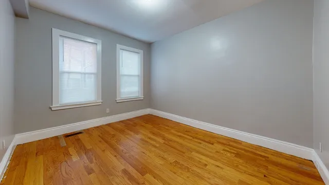 a view of empty room with wooden floor