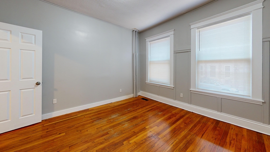 8 Wardman Road, Unit 1 Boston, MA 02119 - Photo 10 of 14 an empty room with wooden floor and windows