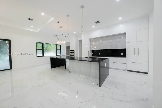 a large white kitchen with a large counter top and stainless steel appliances