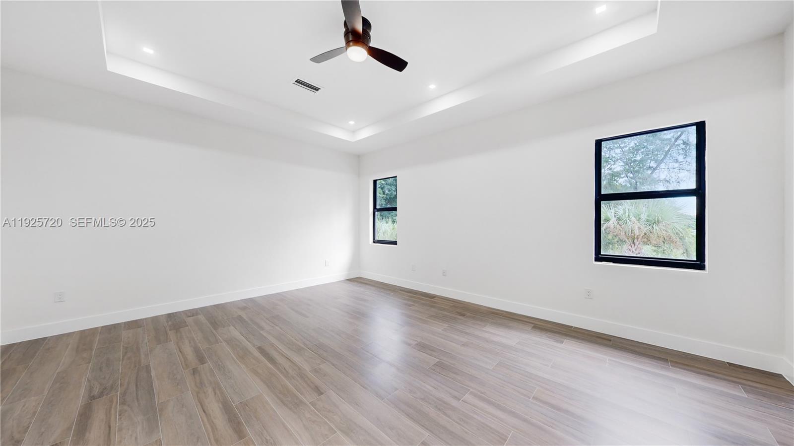 13083 Davie Oaks Drive Davie, FL 33325 - Photo 8 of 10 an empty room with wooden floor chandelier fan and windows