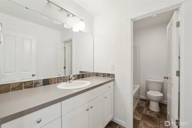 a bathroom with a granite countertop sink a toilet and a mirror