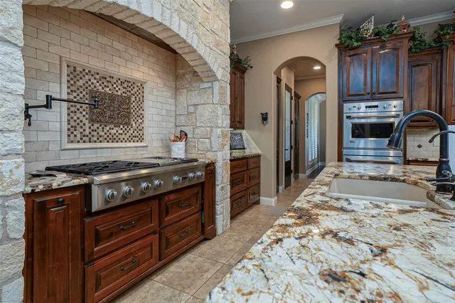 a kitchen with stainless steel appliances granite countertop a stove a sink and a refrigerator