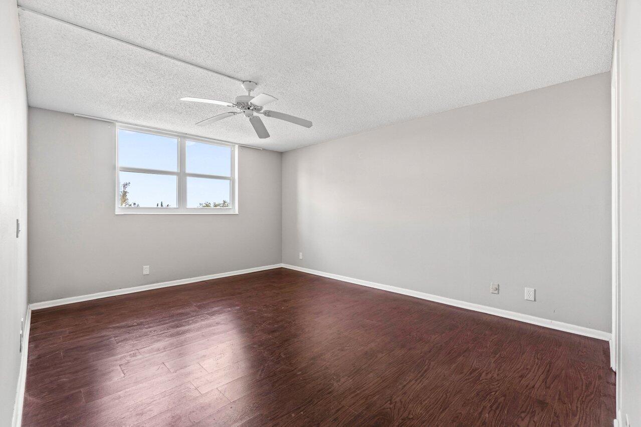 5700 Northwest 2nd Avenue, Unit 401 Boca Raton, FL 33487 - Photo 13 of 30 an empty room with wooden floor ceiling fan and windows