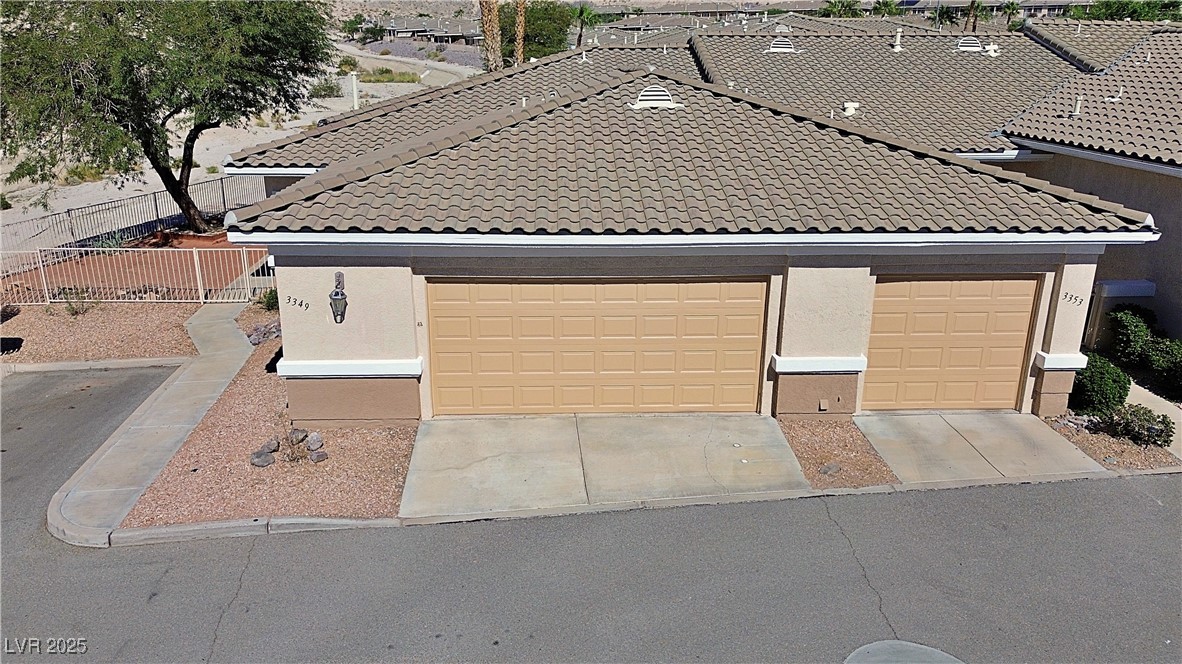 View of front facade featuring stucco siding, a garage, a tiled roof, and concrete driveway