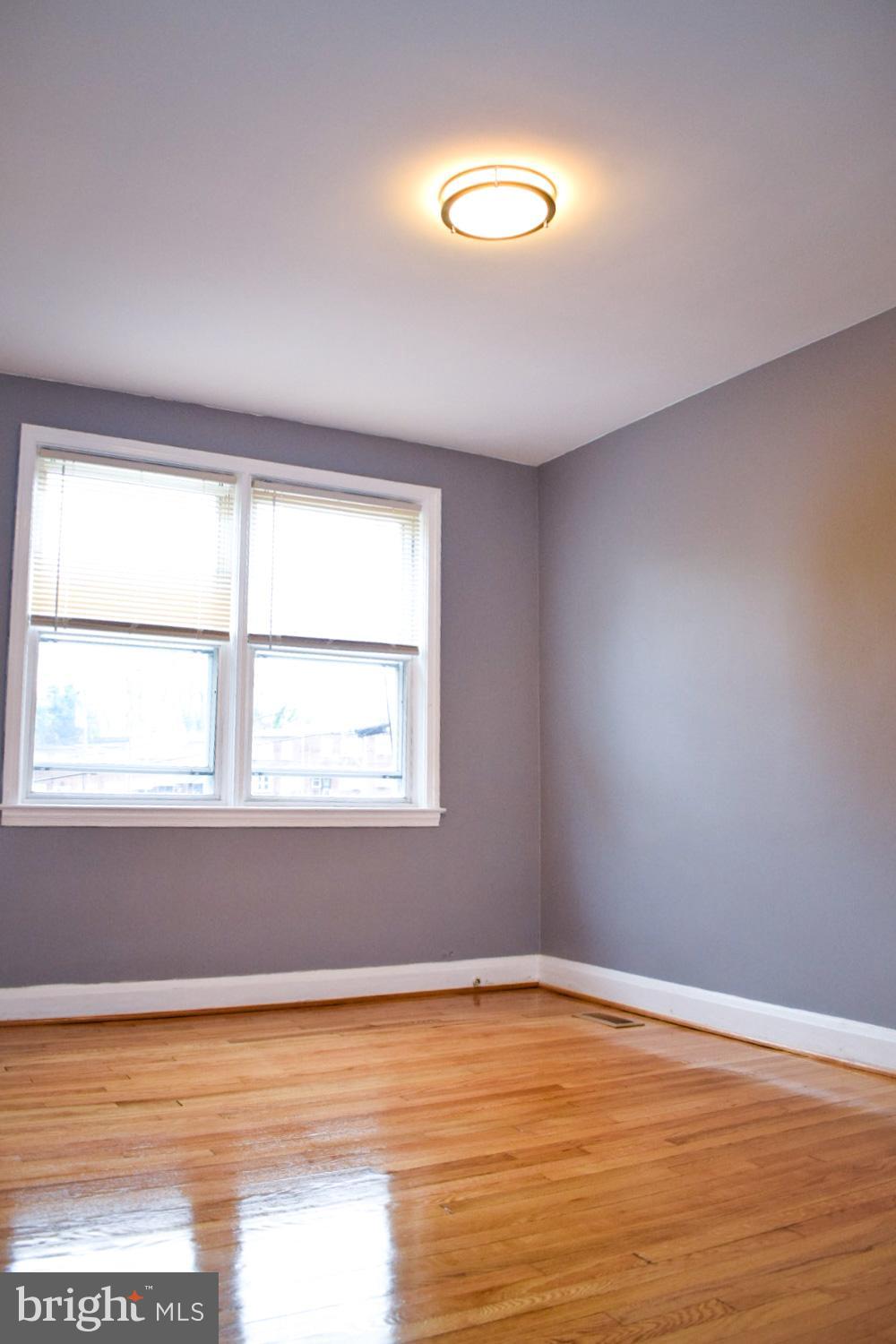 4227 Flowerton Road Baltimore, MD 21229 - Photo 27 of 45 a view of an empty room with wooden floor and a window