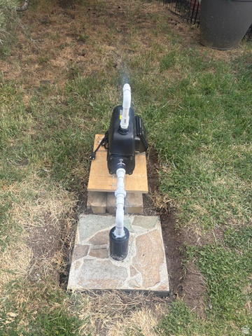 5264 West 5500th Street South Hooper, UT 84315 - Photo 38 of 38 Pump for the well to water entire property Outdoor pump system with white PVC piping, positioned on a wooden base over a flagstone pad