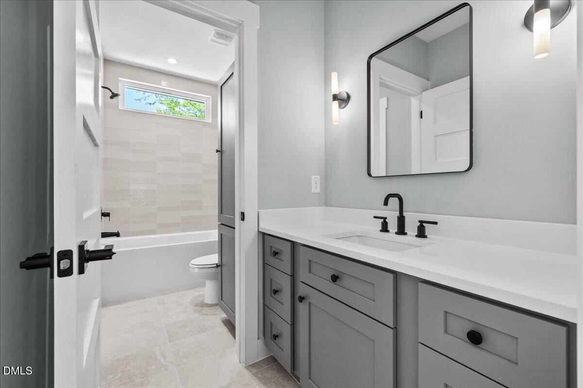 541 Bragg Street Raleigh, NC 27601 - Photo 36 of 44 a bathroom with a granite countertop sink a toilet a mirror and shower