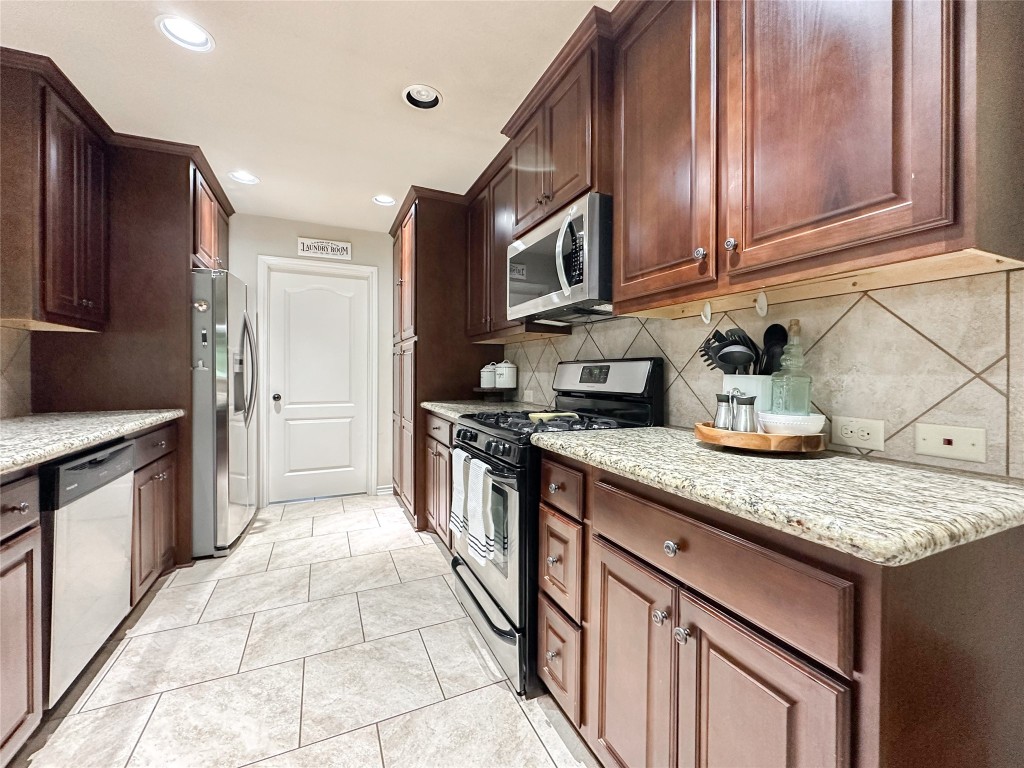2818 Rustic Wood Lane Rosharon, TX 77583 - Photo 12 of 45 a kitchen with stainless steel appliances granite countertop a stove refrigerator and cabinets