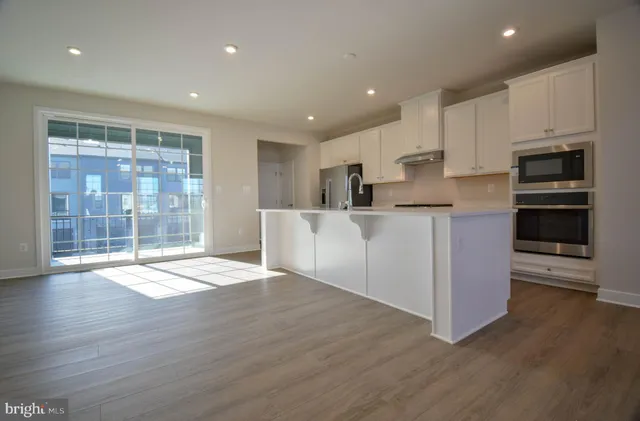 a large kitchen with stainless steel appliances granite countertop a large counter top and a wooden floors