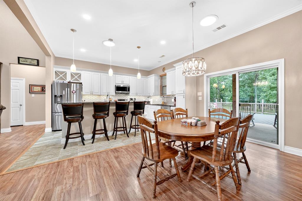 5230 Esquire Estates Road Mabank, TX 75156 - Photo 10 of 39 Open-concept living space with wood-finish flooring, a kitchen island with bar seating, and white cabinetry