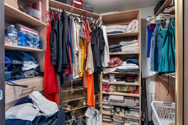 a view of walk in closet with clothes and shoes
