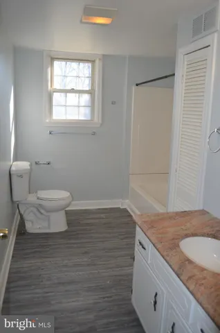 a bathroom with a granite countertop sink a toilet and a window