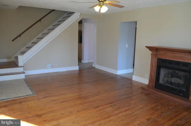 a view of an empty room with wooden floor fireplace and a window