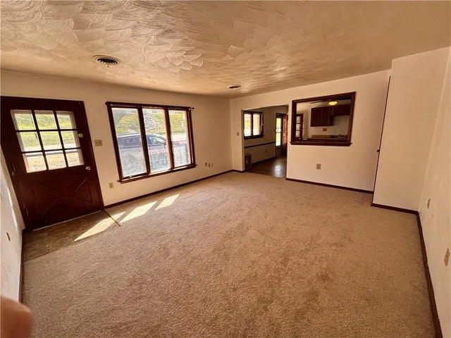 a view of an empty room with a window and a kitchen