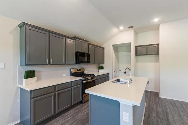 a view of a yard in front of a house with plants and large tree