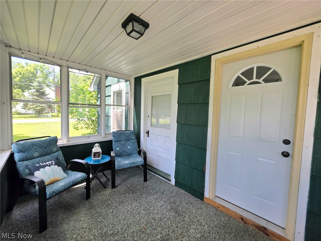 2335 West River Road Newton Falls, OH 44444 - Photo 25 of 36 Screened-in porch featuring a paneled ceiling, exterior wall with green siding, and a white entry door with an arched window insert