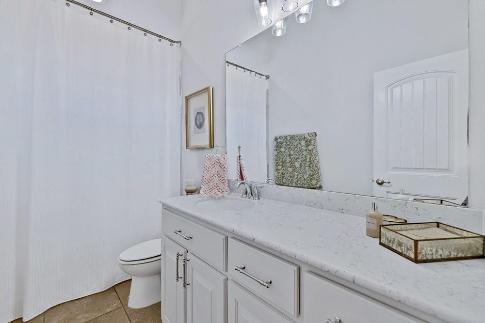 4105 Ranchman Boulevard Denton, TX 76210 - Photo 23 of 39 a bathroom with a granite countertop sink a toilet and a mirror