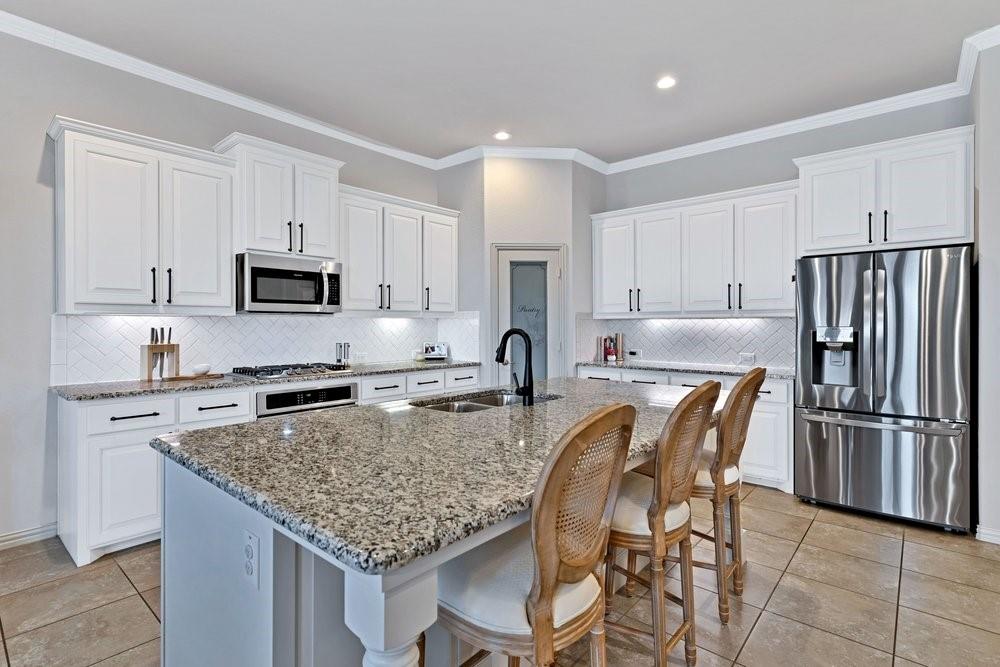 4105 Ranchman Boulevard Denton, TX 76210 - Photo 8 of 39 a kitchen with stainless steel appliances granite countertop a refrigerator a stove a sink a dining table and chairs