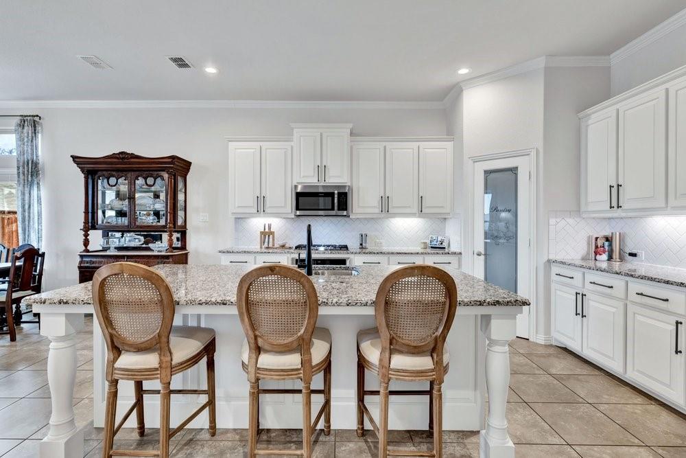 4105 Ranchman Boulevard Denton, TX 76210 - Photo 9 of 39 a kitchen with stainless steel appliances granite countertop a table chairs stove and white cabinets