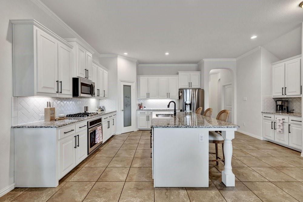 4105 Ranchman Boulevard Denton, TX 76210 - Photo 10 of 39 a kitchen with stainless steel appliances granite countertop a stove top oven a sink a refrigerator and white cabinets