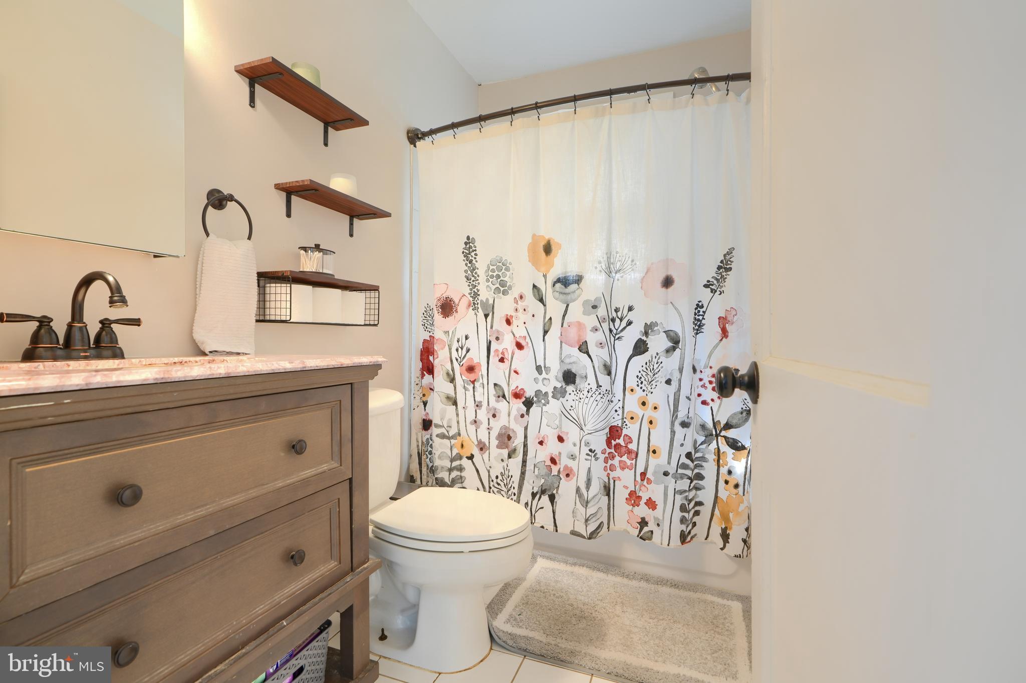 2818 Garnet Road Baltimore, MD 21234 - Photo 20 of 39 a bathroom with a shower curtain sink and a toilet