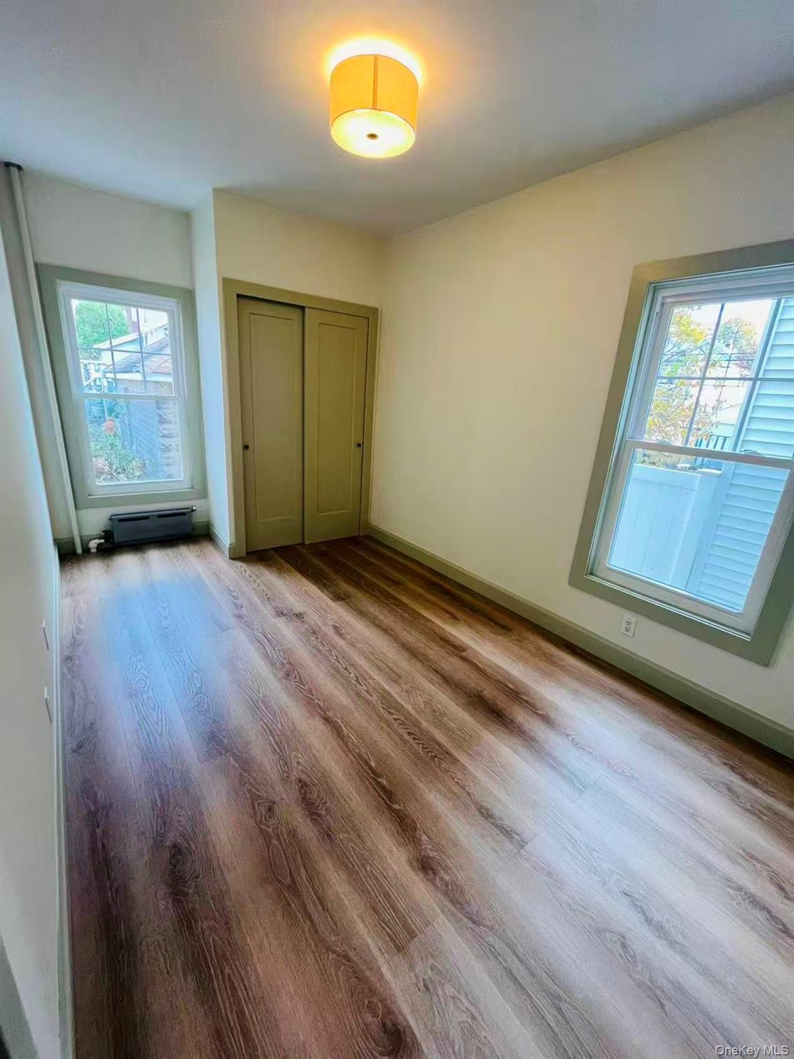 84-33 124th Street Queens, NY 11415 - Photo 14 of 27 an empty room with wooden floor and windows