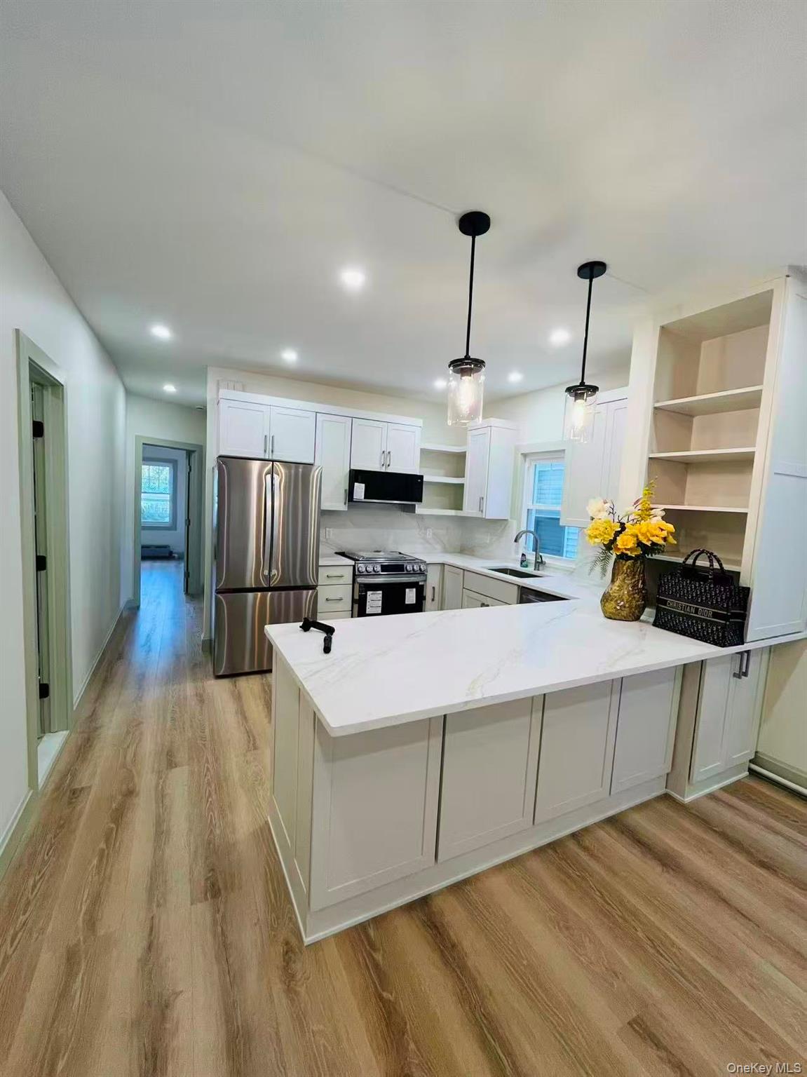 84-33 124th Street Queens, NY 11415 - Photo 10 of 27 a kitchen with stainless steel appliances a refrigerator a stove a sink dishwasher and white cabinets with wooden floor