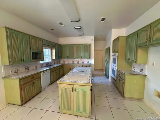 a kitchen with a sink a counter top space stainless steel appliances and cabinets