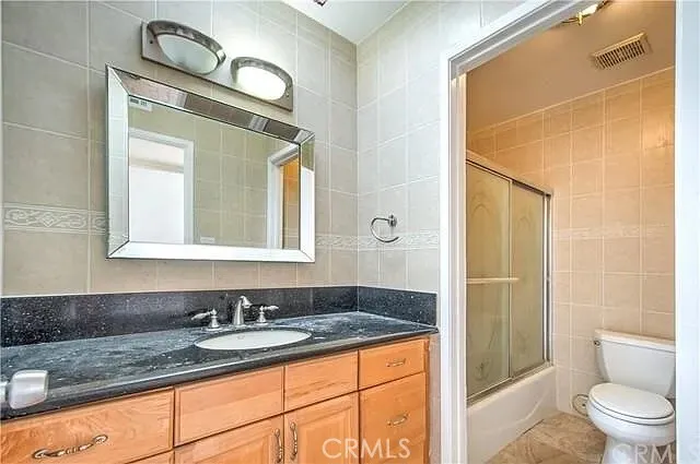 a bathroom with a granite countertop sink toilet and shower