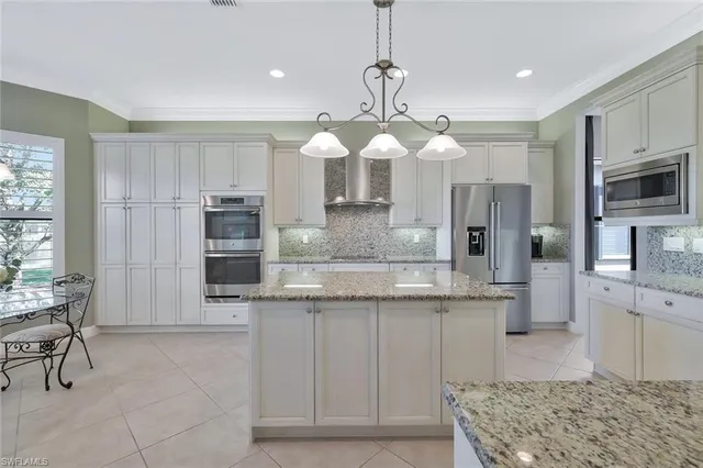 a large kitchen with stainless steel appliances kitchen island granite countertop a stove a sink a refrigerator and a granite counter tops