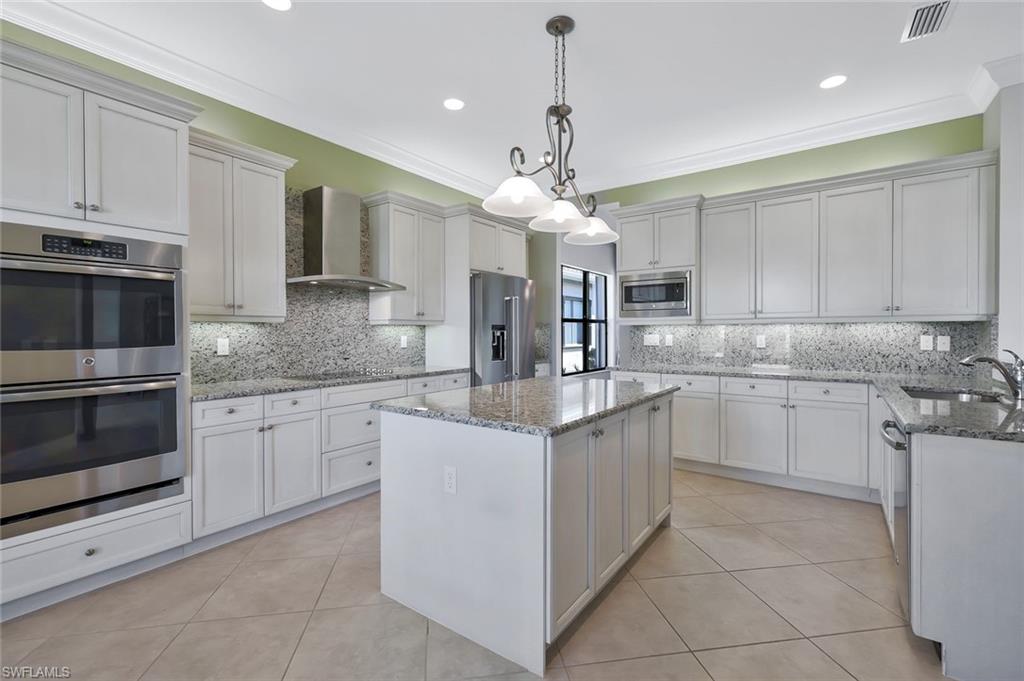 3384 Atlantic Circle Naples, FL 34119 - Photo 8 of 50 a kitchen with kitchen island granite countertop a sink cabinets and stainless steel appliances