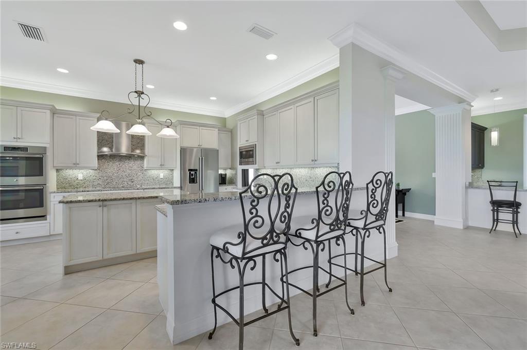 3384 Atlantic Circle Naples, FL 34119 - Photo 9 of 50 a kitchen with stainless steel appliances kitchen island granite countertop a table chairs sink and cabinets