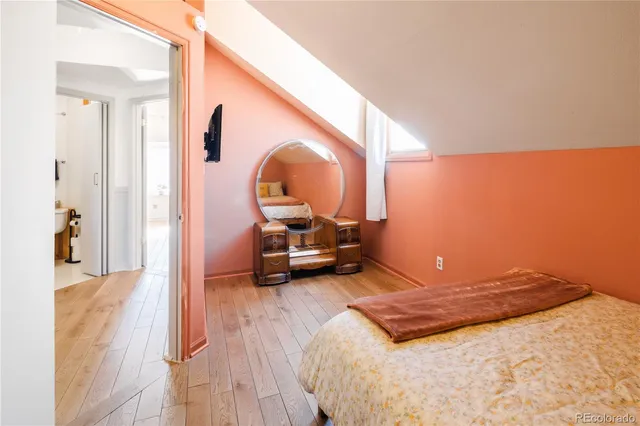 a bedroom with a bed a table and a large mirror next to a window