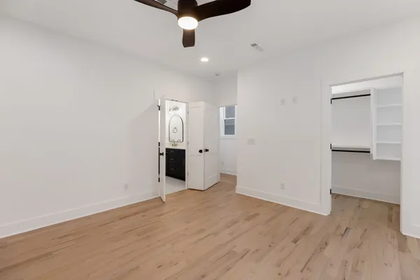 an empty room with wooden floor and ceiling fan