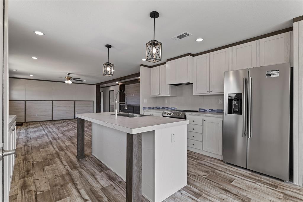 3924 Sandusky Road Whitesboro, TX 76273 - Photo 10 of 22 Kitchen featuring stainless steel appliances, light countertops, hanging light fixtures, a kitchen island with sink, and light wood finished floors