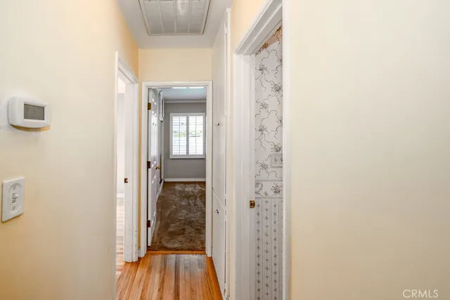 a view of a hallway with wooden floor and a bathroom
