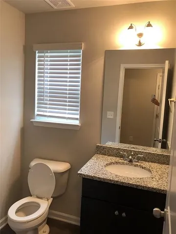 a bathroom with a granite countertop toilet sink and mirror