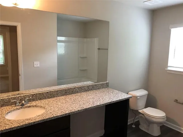 a bathroom with a granite countertop sink a toilet and a mirror