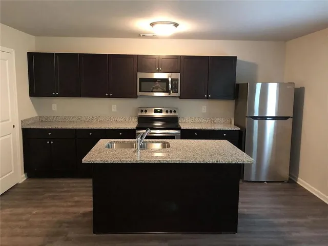a kitchen with a sink a microwave a refrigerator and cabinets