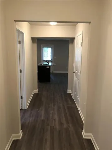 a view of a hallway with wooden floor and a living room