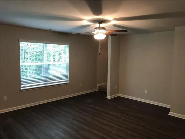 a view of an empty room with wooden floor and a window