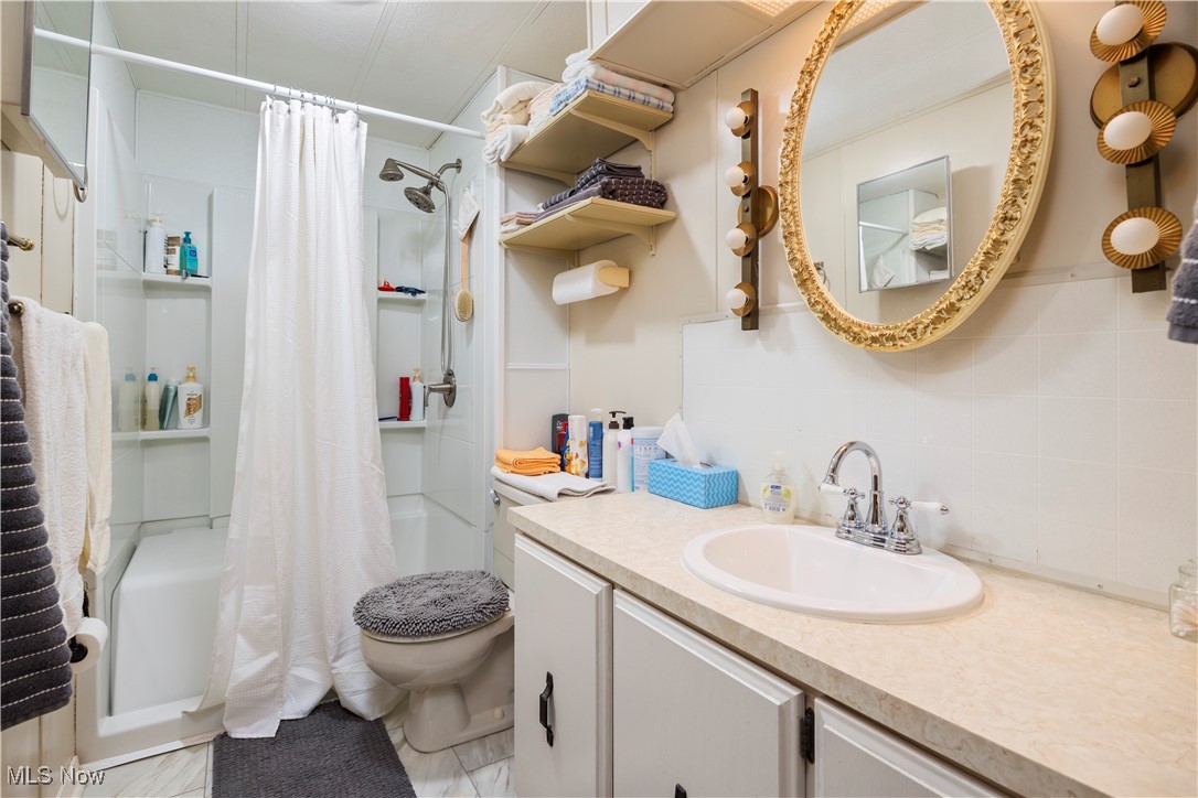 35157 Center Ridge Road, Unit 117 North Ridgeville, OH 44039 - Photo 15 of 21 Bathroom with shower / bathtub combination with curtain, tasteful backsplash, vanity, and toilet
