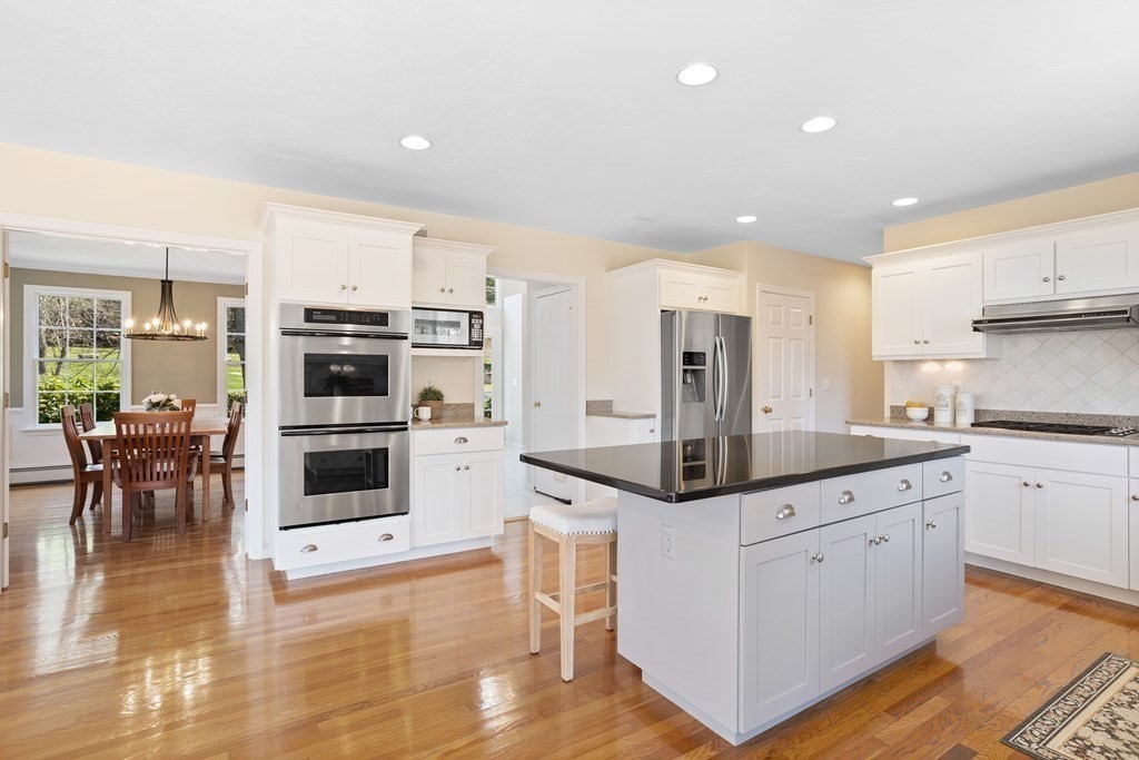 104 Nourse Road Bolton, MA 01740 - Photo 5 of 34 a kitchen with stainless steel appliances kitchen island granite countertop a stove a sink a refrigerator and white cabinets with wooden floor