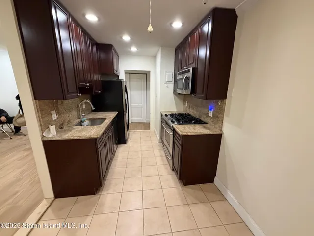 a kitchen with stainless steel appliances granite countertop a refrigerator a sink and wooden cabinets