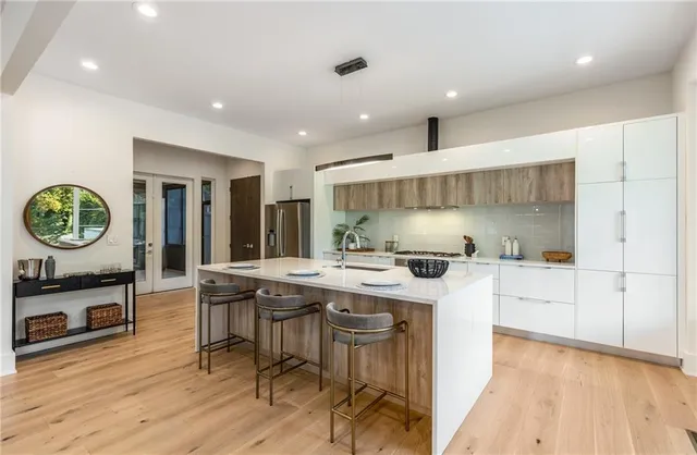 a kitchen with stainless steel appliances granite countertop a stove a refrigerator a sink a dining table and chairs with wooden floor