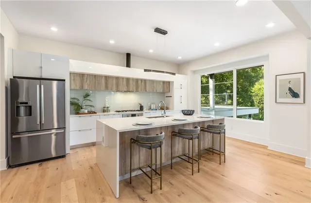 a kitchen with kitchen island granite countertop a stove a sink a dining table and chairs with wooden floor
