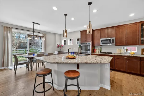 a kitchen with stainless steel appliances granite countertop a stove a sink a microwave a dining table and chairs with wooden floor